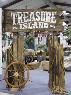 there is a sign that says treasure island on the front and behind it are two wooden ships