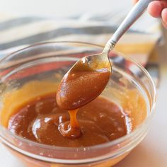 a spoon full of caramel sauce in a glass bowl