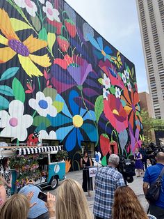 people standing in front of a building painted with flowers