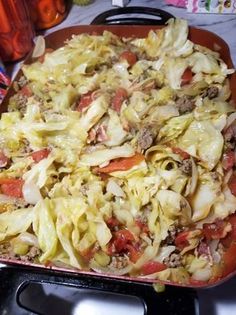 a casserole dish with meat and vegetables in it sitting on a stove top