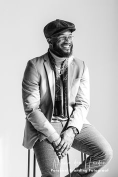 a black and white photo of a man in a suit sitting on a chair smiling