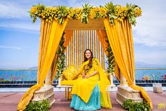 a woman sitting on a bench in front of a gazebo with yellow drapes