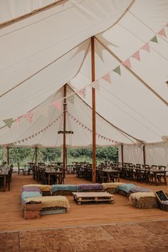 the inside of a large tent with tables and couches in front of it on top of wood flooring