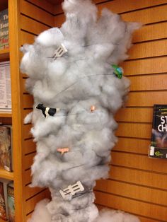 some kind of cloud hanging on the wall in a library with bookshelves behind it