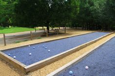 an outdoor play area with balls on the ground and trees in the background at a park