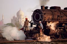 two men standing on top of an old train