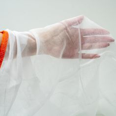 a woman's hand wearing white gloves and an orange bracelet