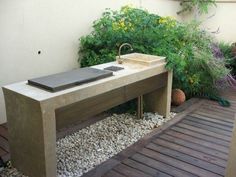 a sink sitting on top of a wooden table next to flowers and plants in a garden