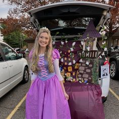 a girl in a purple dress standing next to a car