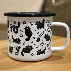 a black and white ceramic mug with cats on it