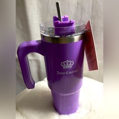 a purple coffee cup sitting on top of a white blanket with a tag attached to it