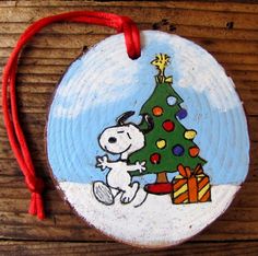 a wooden ornament with a snoopy christmas tree on it and a red string