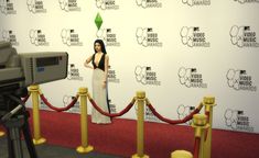 a woman standing in front of a red carpet next to a video camera on a tripod