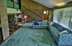 a living room filled with furniture and a fire place next to a stair case in front of a brick wall