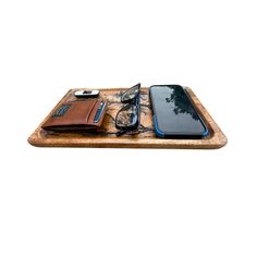 a cell phone, wallet and glasses on a wooden tray