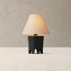 a black table lamp sitting on top of a white counter next to a light bulb