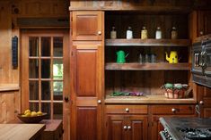 a kitchen with wooden cabinets and shelves filled with dishes on the stove top burners