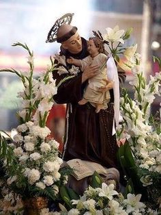 a statue of the virgin mary and child jesus surrounded by flowers