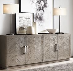 a sideboard with two lamps and pictures on it