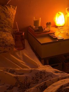 a night stand with two candles on it next to a bed