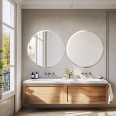 two round mirrors are on the wall above a double sink in a bathroom with wood flooring