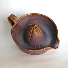 a brown and black ceramic bowl on a white surface