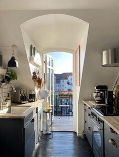 a woman standing in a kitchen next to an open door that leads to a balcony