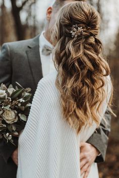 a man and woman standing next to each other in the woods with flowers on their hair