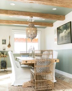 a dining room table with chairs and a birdcage hanging from the ceiling in front of it