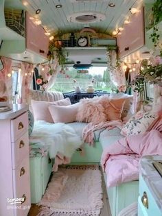 the interior of an rv decorated in pastel colors and with lights strung from the ceiling