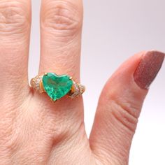 Kapow! 4ct Colombian emerald heart set in 18k yellow gold flanked with .50cts of diamonds. Emerald is an incredible glowing green with natural inclusions and measures 11.6x11.7mm. Ring size 8.75.Sizing availableLayaway available Colombian Emeralds, Turquoise Ring, Statement Rings, Heart Ring, Emerald, Ring Size, Diamonds, Yellow Gold, Turquoise