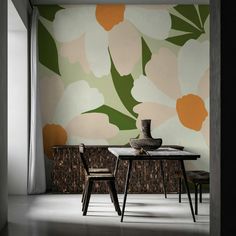 a dining room table with two chairs and a vase on top of it in front of a floral wallpaper