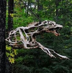 an animal made out of tree branches in the middle of a forest with lots of trees