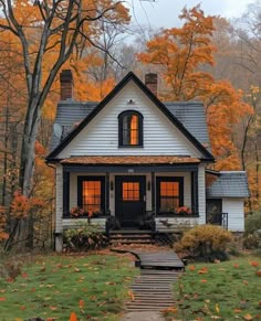 a white house in the fall with leaves on the ground and trees all around it