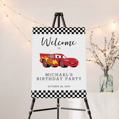 a welcome sign for a birthday party with a race car on it and lights in the background