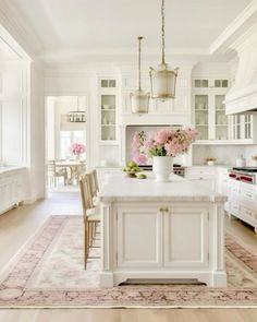 a kitchen with white cabinets and pink flowers on the island