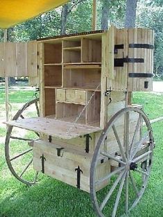 an old fashioned wooden cart with wheels and drawers on the back is sitting in the grass