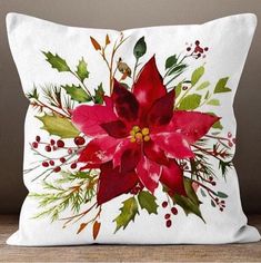 a white pillow with a red poinsettia and holly leaves on it's side