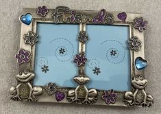 a silver frame with two frogs and hearts