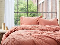 an unmade bed in front of a large window