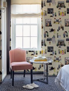 a chair and table in front of a window with pictures on the wall behind it