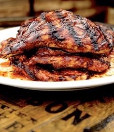 a white plate topped with meat covered in gravy on top of a wooden table