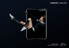 an advertisement for the samsung galaxy fold phone shows a woman swinging on a rope with her feet