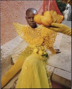 a young boy sitting on the ground with yellow flowers in his hair and wearing an elaborate headdress