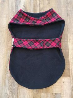 a black and red plaid dog coat on a wooden floor