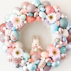 a wreath made out of eggs and flowers with a bunny sitting in the middle surrounded by other decorations