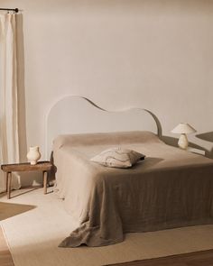 a bed with a white headboard sitting on top of a wooden floor next to a window