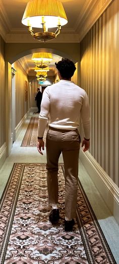 a person walking down a hallway with a lamp on the ceiling and carpeted floor