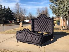 two black beds sitting on the side of a sidewalk next to a tree and house