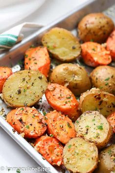 roasted potatoes and carrots with herbs in a baking pan on a table top, ready to be eaten